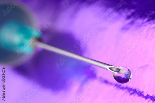 Syringe needle and a drop of a transparent substance. close-up