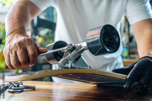 Obraz na płótnie man use the socket tool to remove the nuts on skateboard and adjusts suspension in workshop, Skateboard maintenance and repair concept. Selective focus w salonie