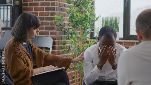 People at aa meeting comforting man with mental health issues and addiction. Person complaining about alcoholism and making confession in front of group at rehabilitation program. photo