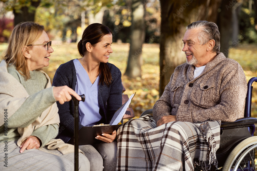 Smiling nurse discussing documents with senior couple at park Smiling nurse discussing documents with senior couple at park