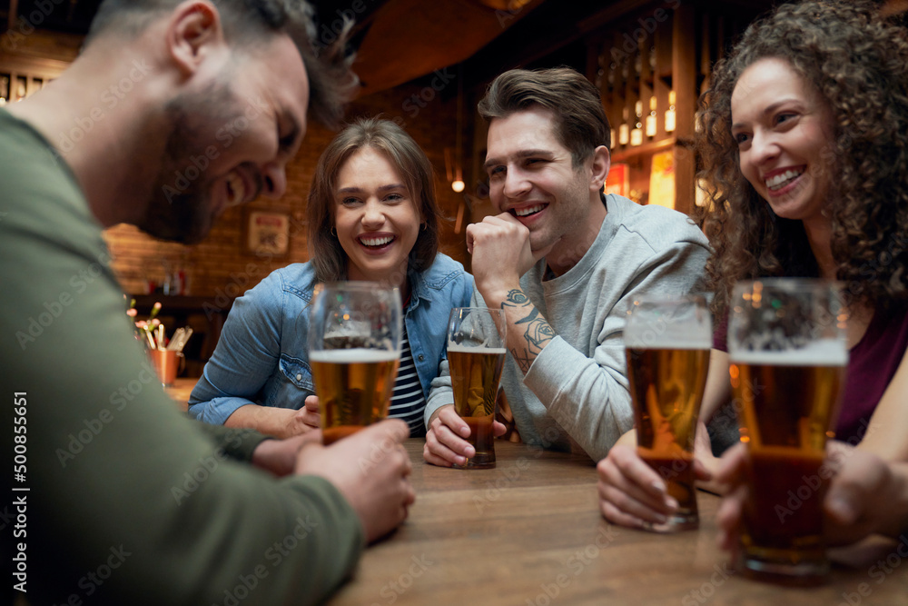 Group of happy friends having beer and socializing in a pub Group of happy friends having beer and socializing in a pub