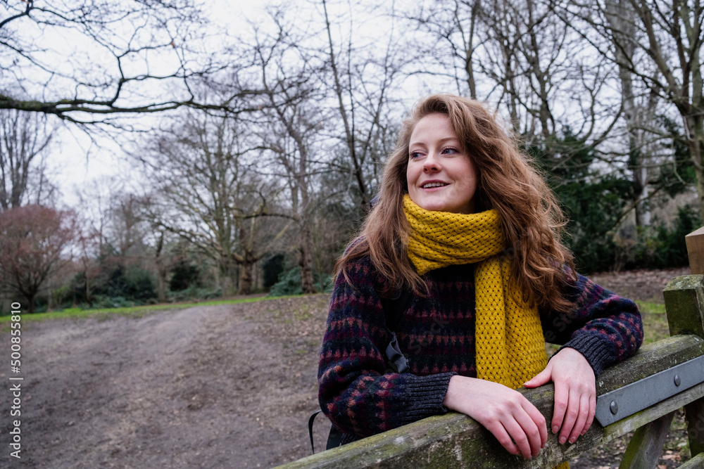 Smiling young woman in yellow scarf standing by gate in forest Smiling young woman in yellow scarf standing by gate in forest
