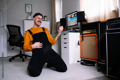 Man playing air guitar kneeling in home studio photo