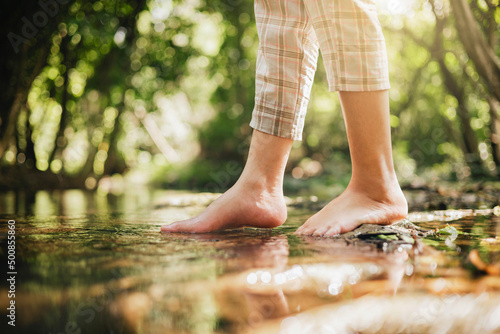 woman wading barefoot in stream in nature forest photo