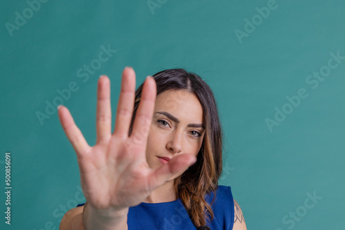 Young woman gesturing stop with hand against blue background photo
