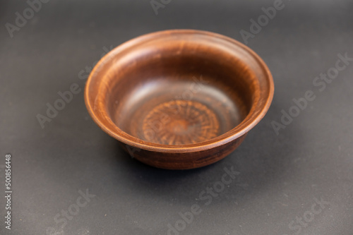 An empty clay bowl against a black background. Brown new fired clay dishes. Selective focus.