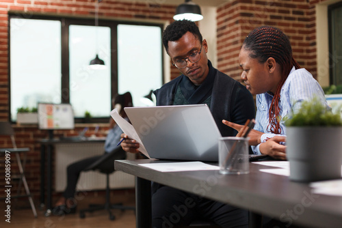 Marketing company financial department team brainstorming ideas to be used by boardroom executives. African american office workers reviewing accounting documentation papers