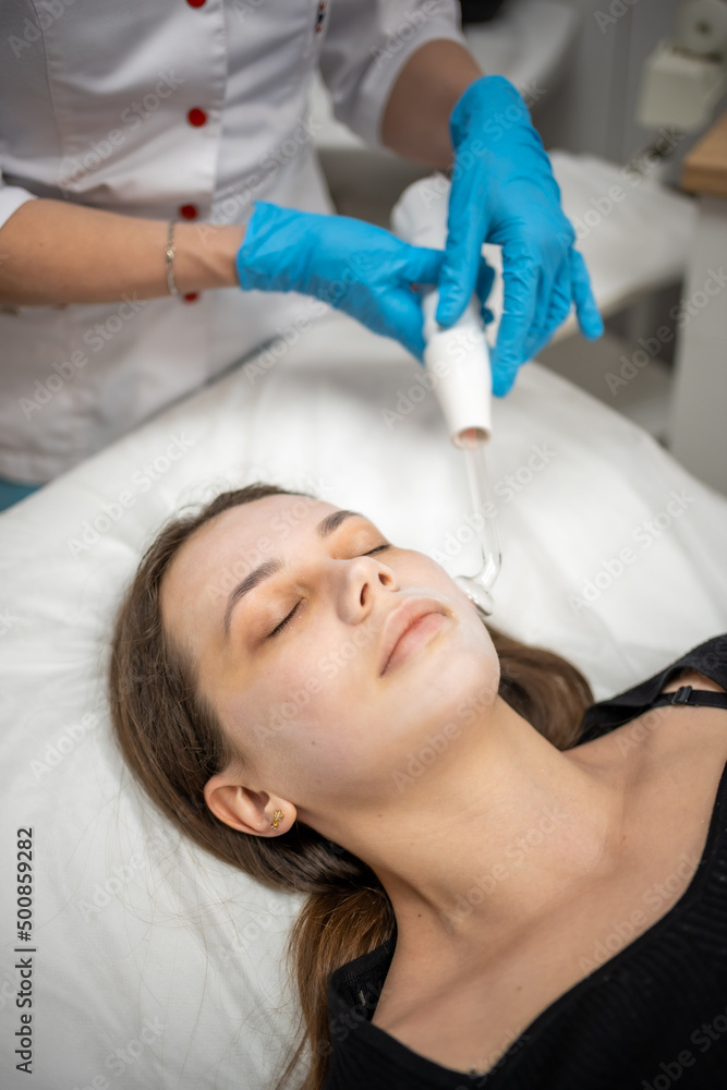 Beautician uses the darsonval device on the client's face. Professional skin care in the salon. The concept of cosmetology and rejuvenation. Beautician uses the darsonval device on the client's face. Professional skin care in the salon. The concept of cosmetology and rejuvenation.