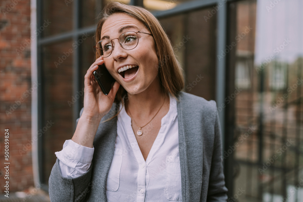 Happy woman talking on mobile phone in front of building Happy woman talking on mobile phone in front of building