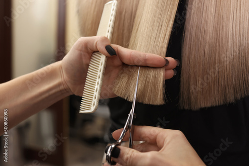 Professional hairdresser cutting woman's hair in salon, closeup