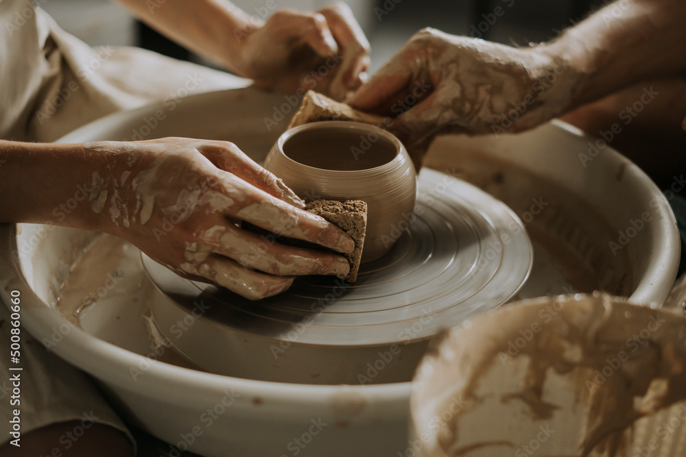 Woman with young man shaping bowl on potter's wheel in workshop Woman with young man shaping bowl on potter's wheel in workshop