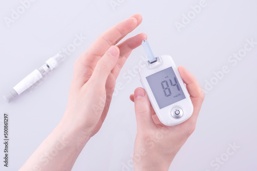 Human using a glucometer to measure and test blood glucose levels from a finger. photo