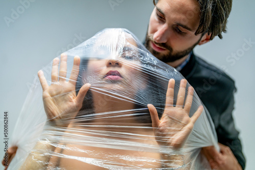 Man watching woman vanishing under in foil photo