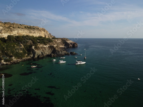 Aerial panoramic view of seascape with crystal clear azure sea and rocky shores. Yachts in a beautiful lagoon on backdrop of rocks. The concept of an ideal destination for summer travel and vacation.