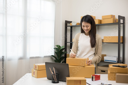 Young asian business woman writing address to sending product to customer. Online business working at home. Startup Small business owner entrepreneur © Chanakon