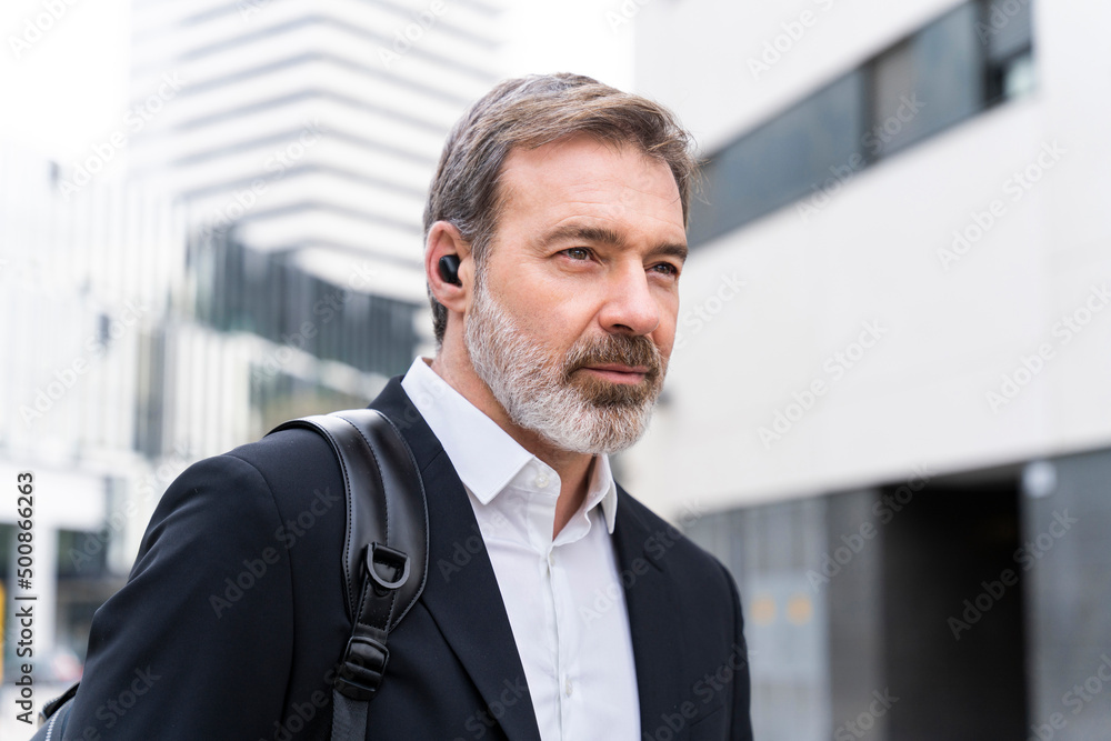Mature businessman wearing wireless in-ear headphones Mature businessman wearing wireless in-ear headphones
