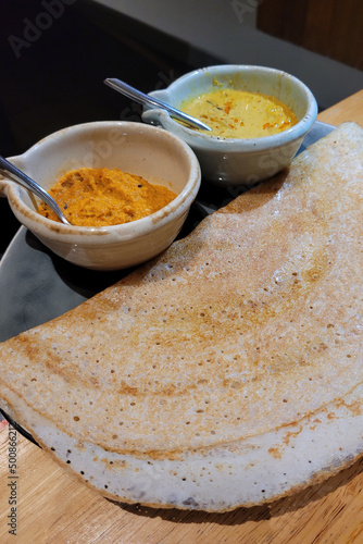 A plate of dosa also known as thosai or tosai with dipping sauce. A dosa is a thin crepe originating from South India, made from a fermented batter predominantly consisting of lentils and rice. photo