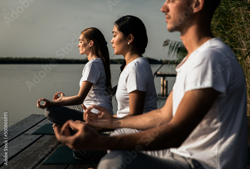 Group of people doing yoga exercises by the lake. © Zoran Zeremski