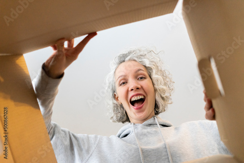 Happy woman opening cardboard box at home