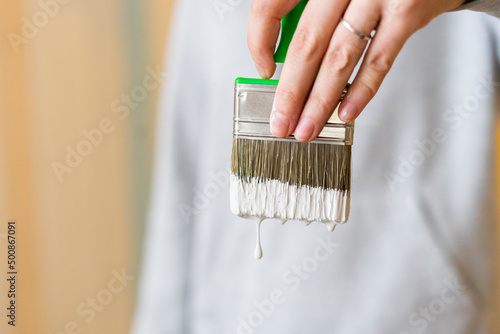 Woman holding paintbrush with dripping white paint