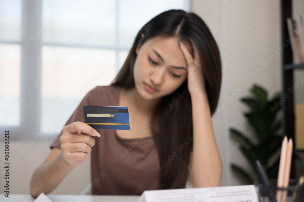 A young Asian woman is stressed because she looks at many expense bills and she has no money to pay them. Not enough money on credit card to pay A young Asian woman is stressed because she looks at many expense bills and she has no money to pay them. Not enough money on credit card to pay