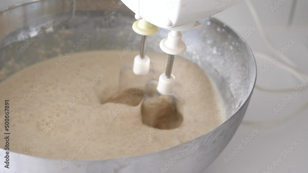Close up of a mixer mixing pancake batter in a big silver bowl Close up of a mixer mixing pancake batter in a big silver bowl