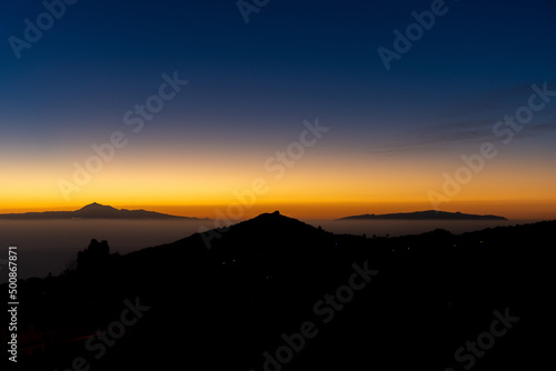 Tenerife and La Gomera islands above the horizon at sunrise with the "Montaña de la Breña" in the middle. Seen from Breña Baja town, in La Palma (Canary Islands, Spain)