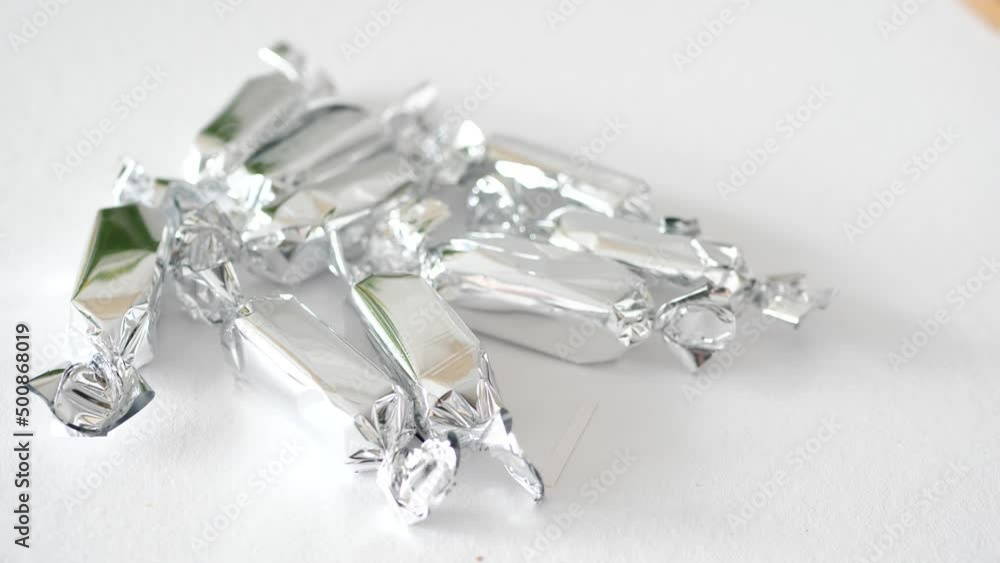Womans hand taking silver candy from a table Womans hand taking silver candy from a table
