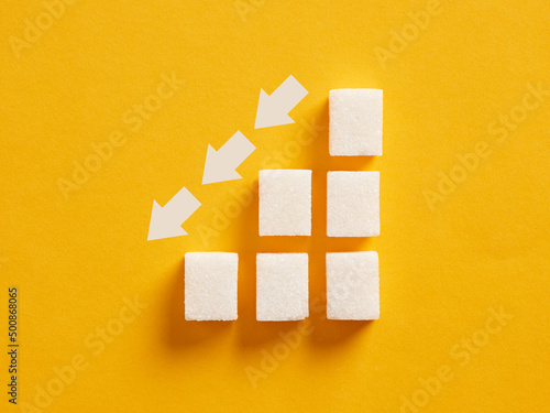 Billede på lærred Ascending sugar cube graph with descending arrows indicating to reduce sugar intake and healthy nutrition