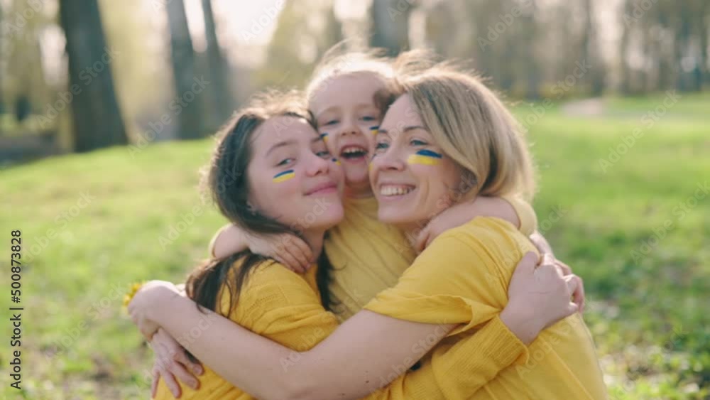 Portrait of Ukrainian family. Mom with two little daughters hugging and smiling in nature on sunny day. Portrait of Ukrainian family. Mom with two little daughters hugging and smiling in nature on sunny day.
