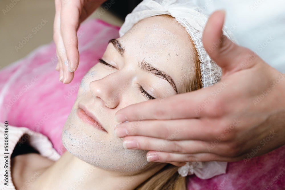 A cosmetologist does a peeling of a young woman's face A cosmetologist does a peeling of a young woman's face