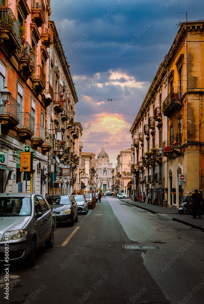 Main street of Catania with the facade of its Cathedral in the background at sunset