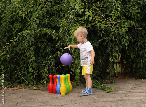 Fotografija Toddler plays active outdoors games. bowling pins.