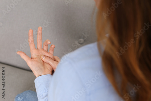 Woman suffering from trigger finger on sofa, closeup