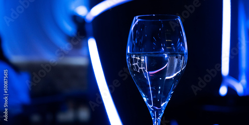 A glass of wine on the bar. Blue neon in the club restaurant close-up. Alcohol at the party