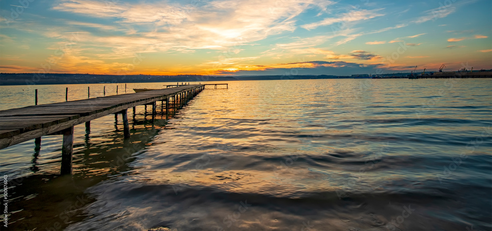 Obraz premium Panoramic view of stunning twilight at the shore with a wooden jetty