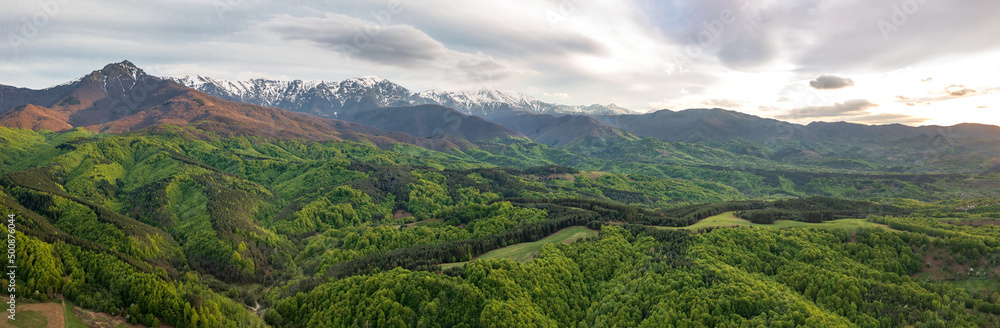 Amazing panoramic view from a drone of the mountain with snow peaks and green hills.