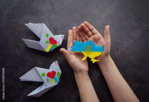 Hands holding the shape of Ukraine border with color flag