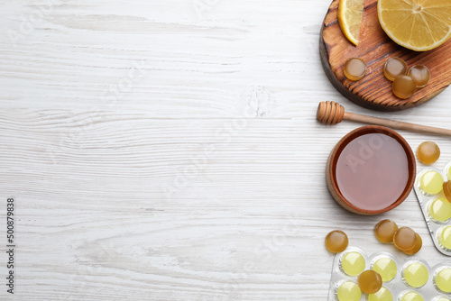 Cough drops, lemon and honey on white wooden table, flat lay. Space for text