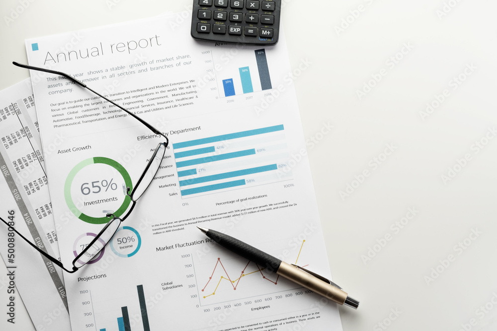 Mockup annual report sheet with charts and graphs, pen, calculator and eyeglasses on white desk. Accounting, business, finance, tax and office concepts with copy space. Mockup annual report sheet with charts and graphs, pen, calculator and eyeglasses on white desk. Accounting, business, finance, tax and office concepts with copy space.