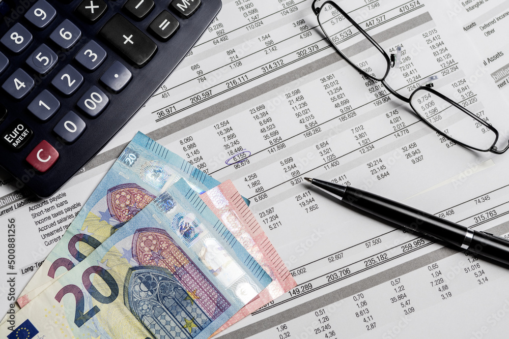 Euro banknotes, pen, calculator and eyeglasses on a mockup balance sheet. Accounting, business, finance and tax concepts. Euro banknotes, pen, calculator and eyeglasses on a mockup balance sheet. Accounting, business, finance and tax concepts.