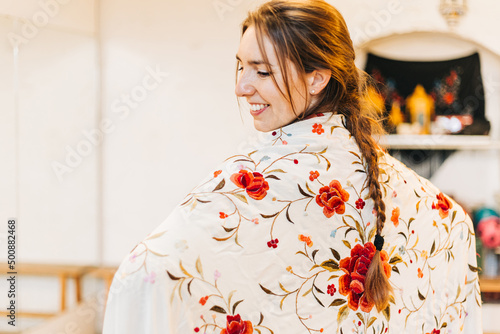 portrait of a happy female flamenco dancer with a embroidered floral shawl on her back smiling