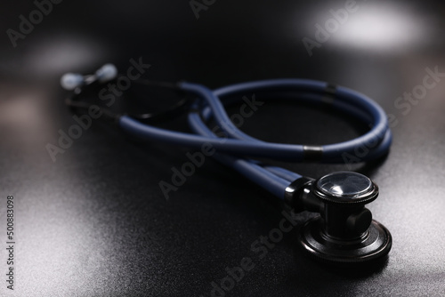 Leinwand Poster Dark blue medical stethoscope on black surface