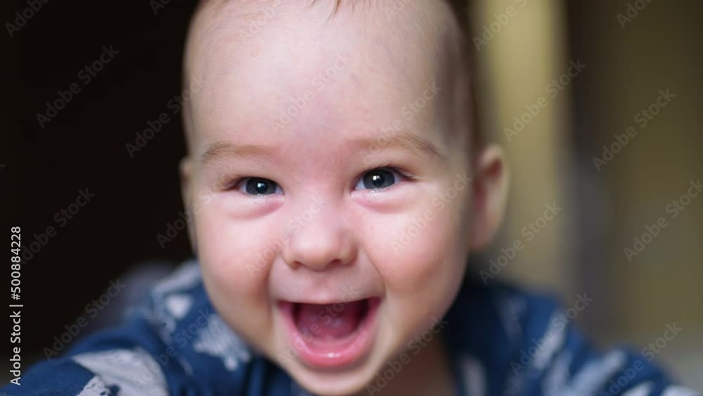Adorable Caucasian kid laughing cheerfully to the camera. Close up portrait of adorable baby boy with grey eyes. Adorable Caucasian kid laughing cheerfully to the camera. Close up portrait of adorable baby boy with grey eyes.