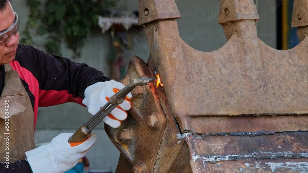 Worker cutting steel with a gas torch. Man cutting steel with propane and oxygen. Processes that use fuel gases and oxygen to weld and cut metals. Worker cutting steel with a gas torch. Man cutting steel with propane and oxygen. Processes that use fuel gases and oxygen to weld and cut metals.