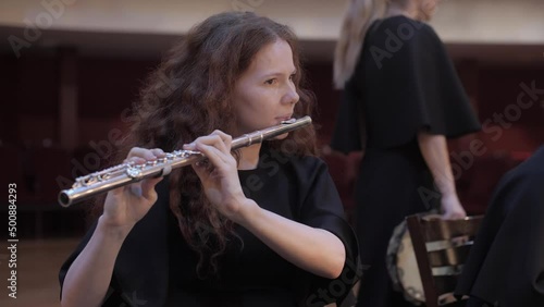 girl plays the flute by notes in the theater, rehearsal before the concert  photo