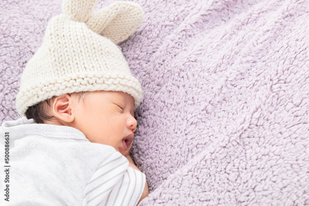 Newborn asian baby curled up sleeping on a blanket. Baby boy wearing a knitted hat, Newborn baby aged 0-1 months lying in bed. Copy space and top view Newborn asian baby curled up sleeping on a blanket. Baby boy wearing a knitted hat, Newborn baby aged 0-1 months lying in bed. Copy space and top view