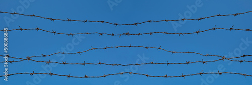 Five barb wires against the blue clear sky