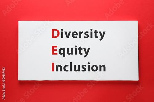 Paper with abbreviation DEI - Diversity, Equity, Inclusion on red background, top view