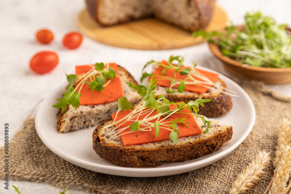 Grain bread sandwiches with red tomato cheese and microgreen on gray, side view, selective focus.